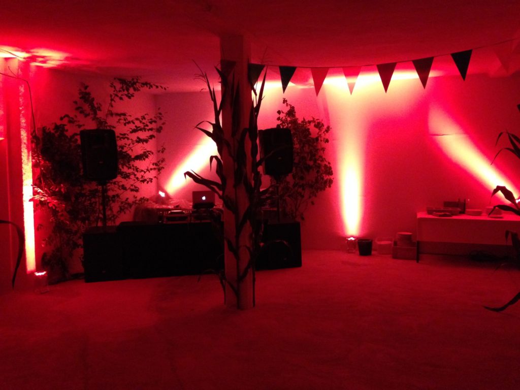 Partyraum mit rotem Stimmungslicht und DJ-Pult