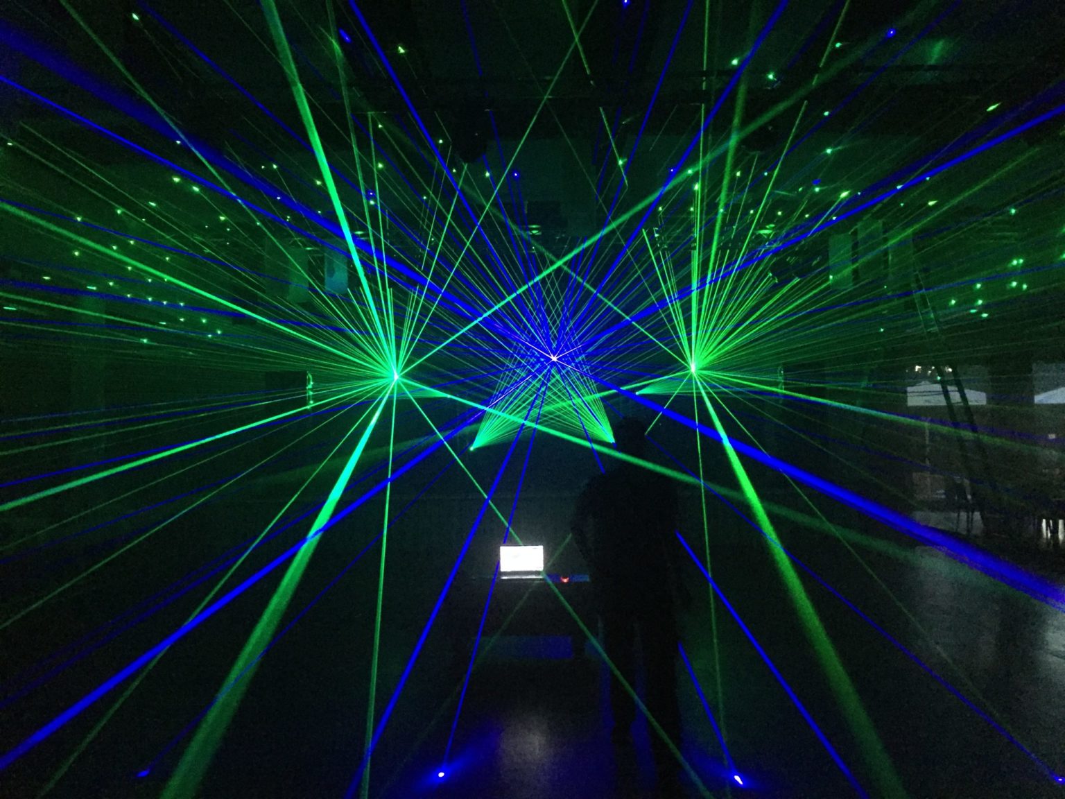 Lasershow in einer Halle mit grünen und blauen Strahlen